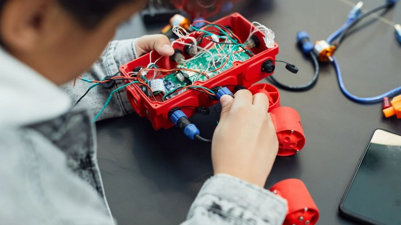 Ortaokul öğrencisi robotik setinin kablolarını bağlıyor